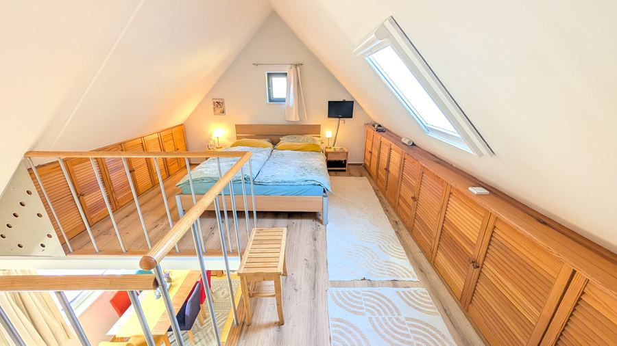 Galerie mit Doppelbett, Dachfenster und Einbauschränken unter der Dachschräge